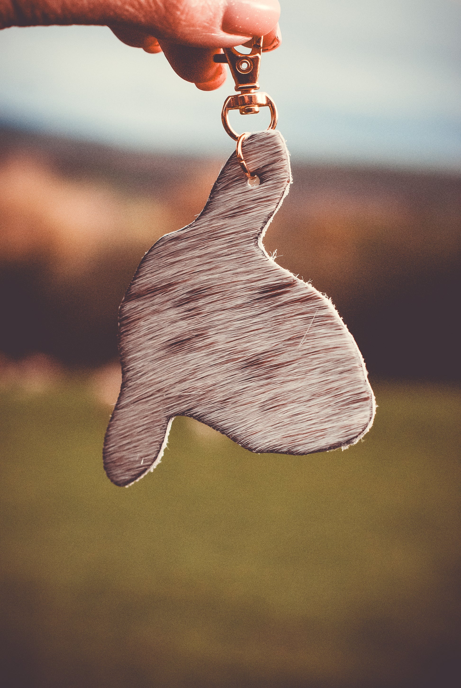 Mottled animal-shaped keyring with gold metal ring, held by a hand