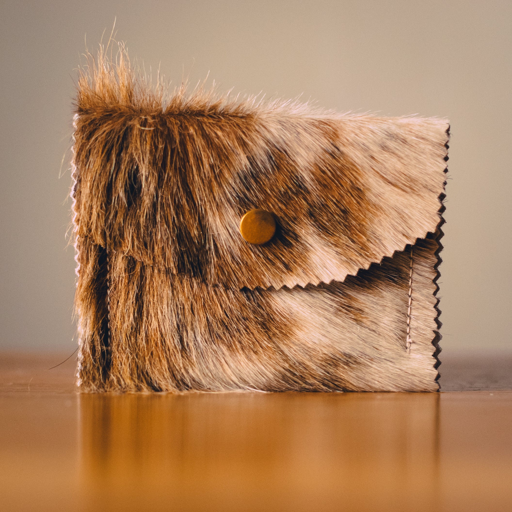 Small cowhide purse with flap, brown-and-cream hide pattern, round snap button