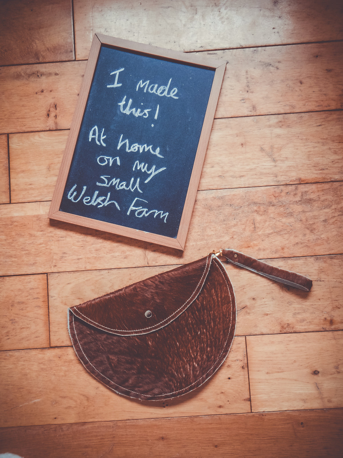 Brown cowhide moon clutch bag with wrist strap and round snap button