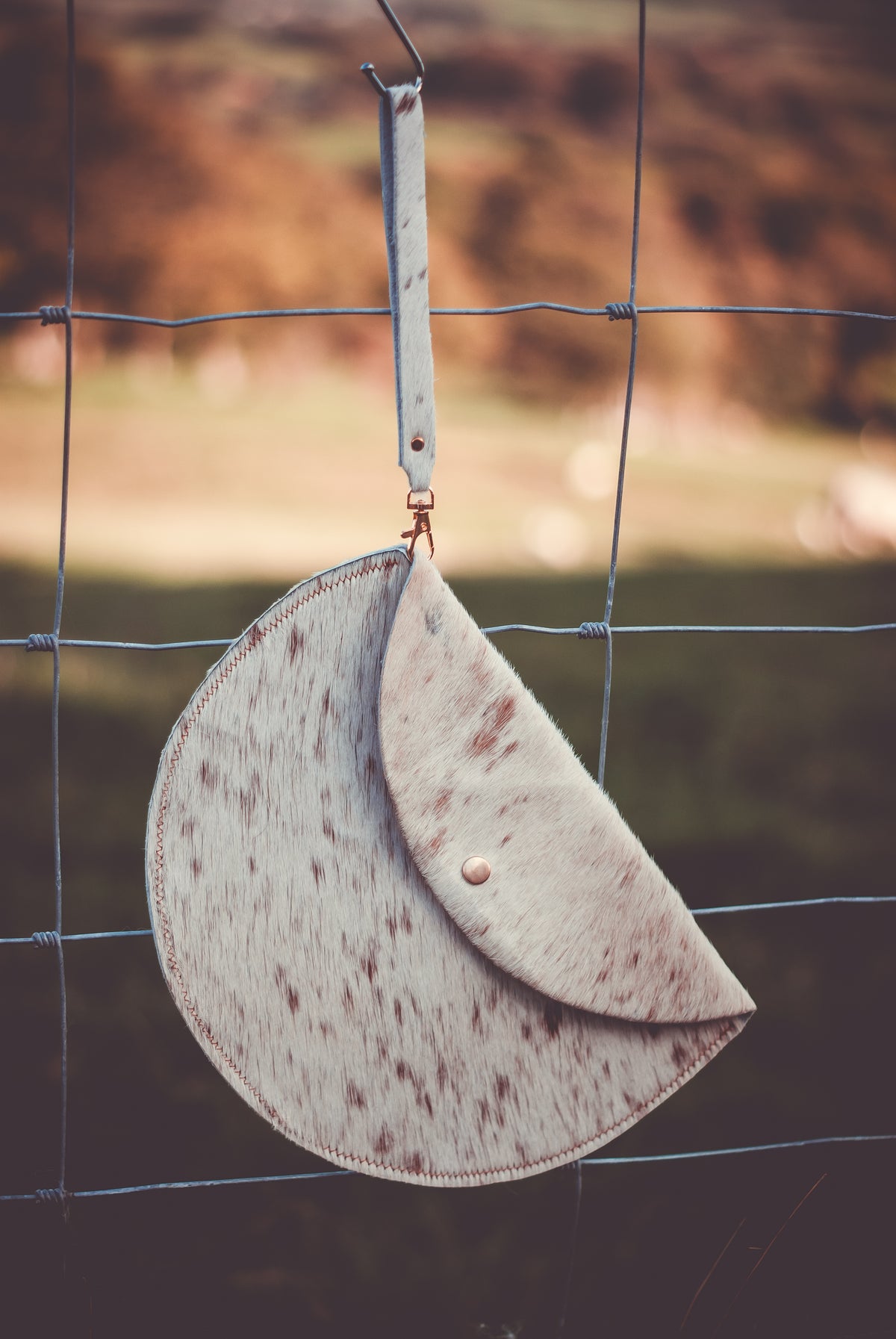 Cowhide moon clutch bag with curved flap and short hanging strap, speckled light hide