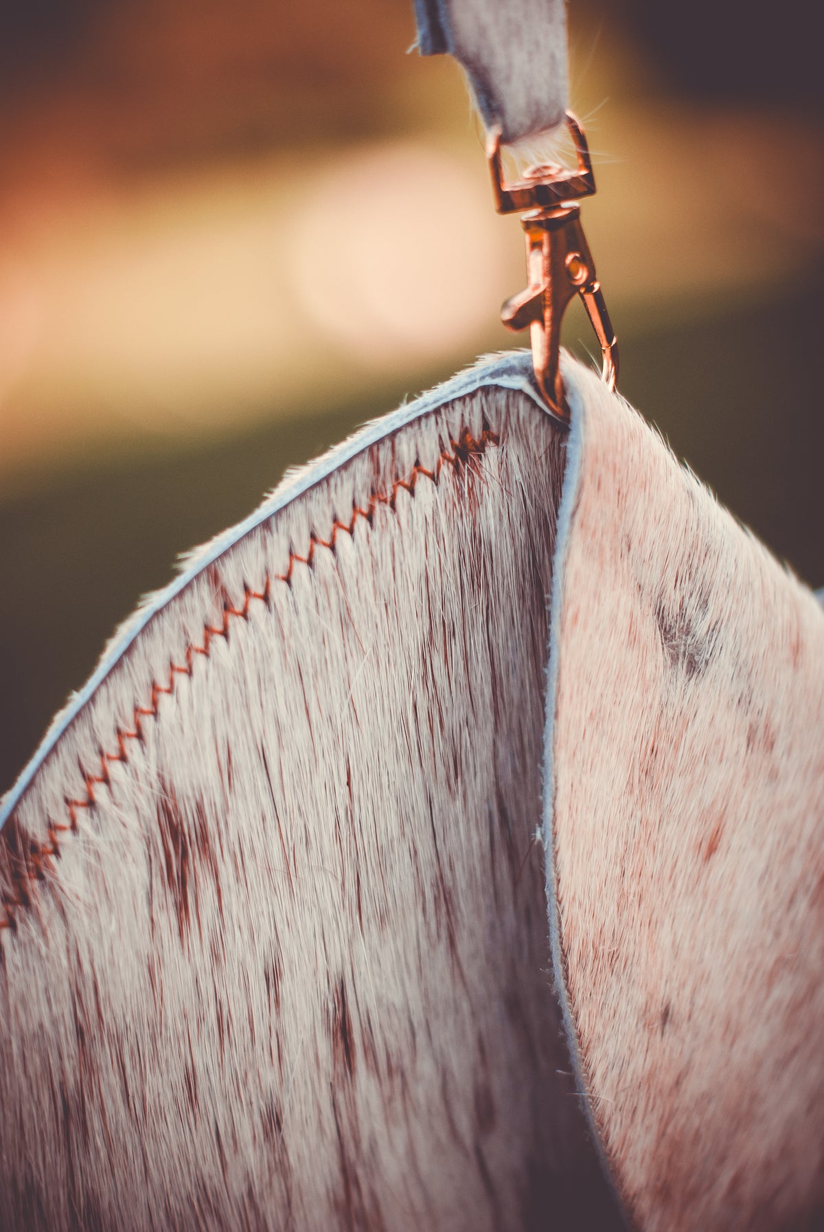 Speckled cowhide moon clutch bag close-up with curved edge and metal clasp detail