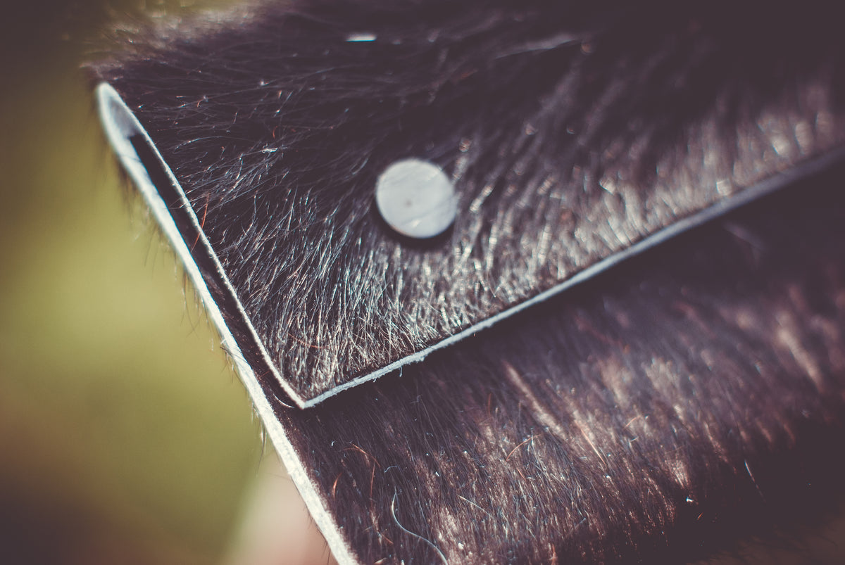 Cowhide purse corner close-up with silver snap and angled leather seam