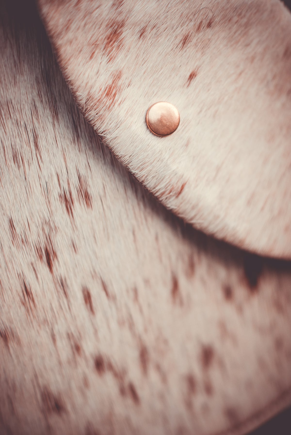Cowhide moon clutch bag flap with round metal snap button on speckled light hide