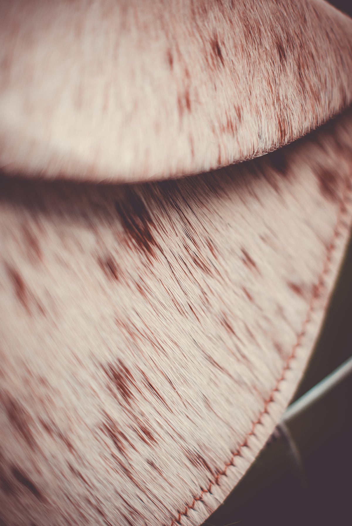 Speckled cowhide moon clutch bag with stitched curved edge and reinforced seam