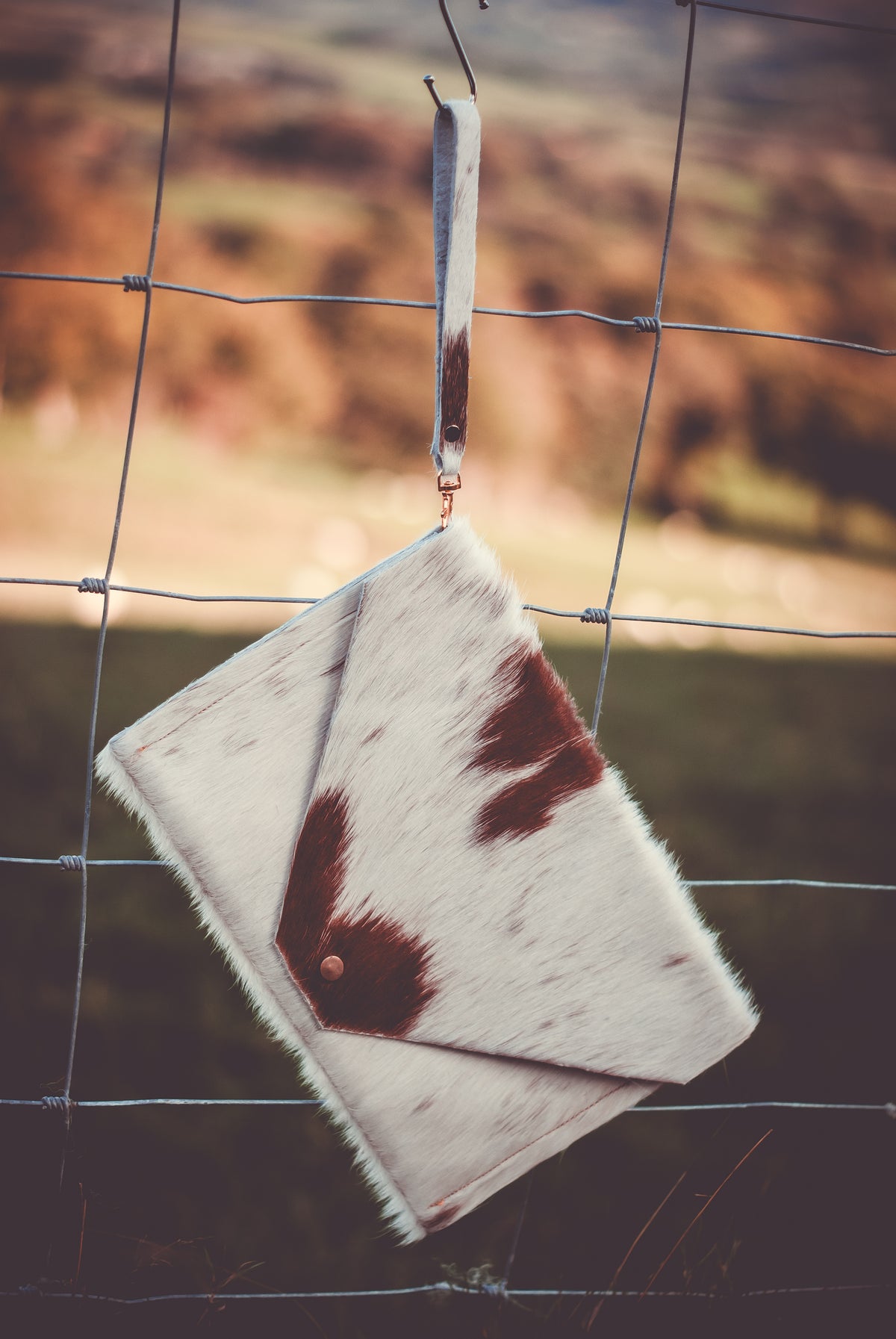 Cowhide envelope clutch bag with wrist strap, white with dark brown patches