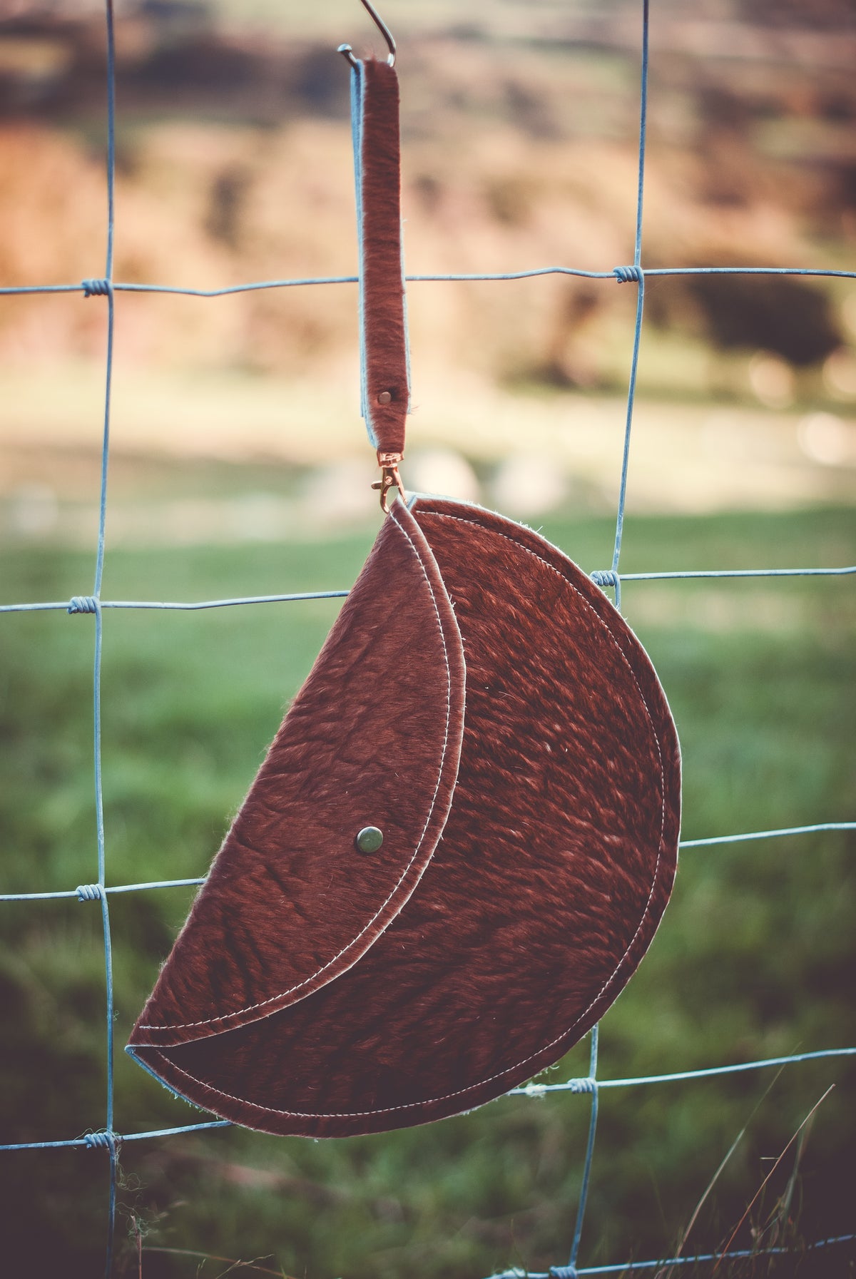 Brown cowhide moon clutch bag with contrast edging and round snap button