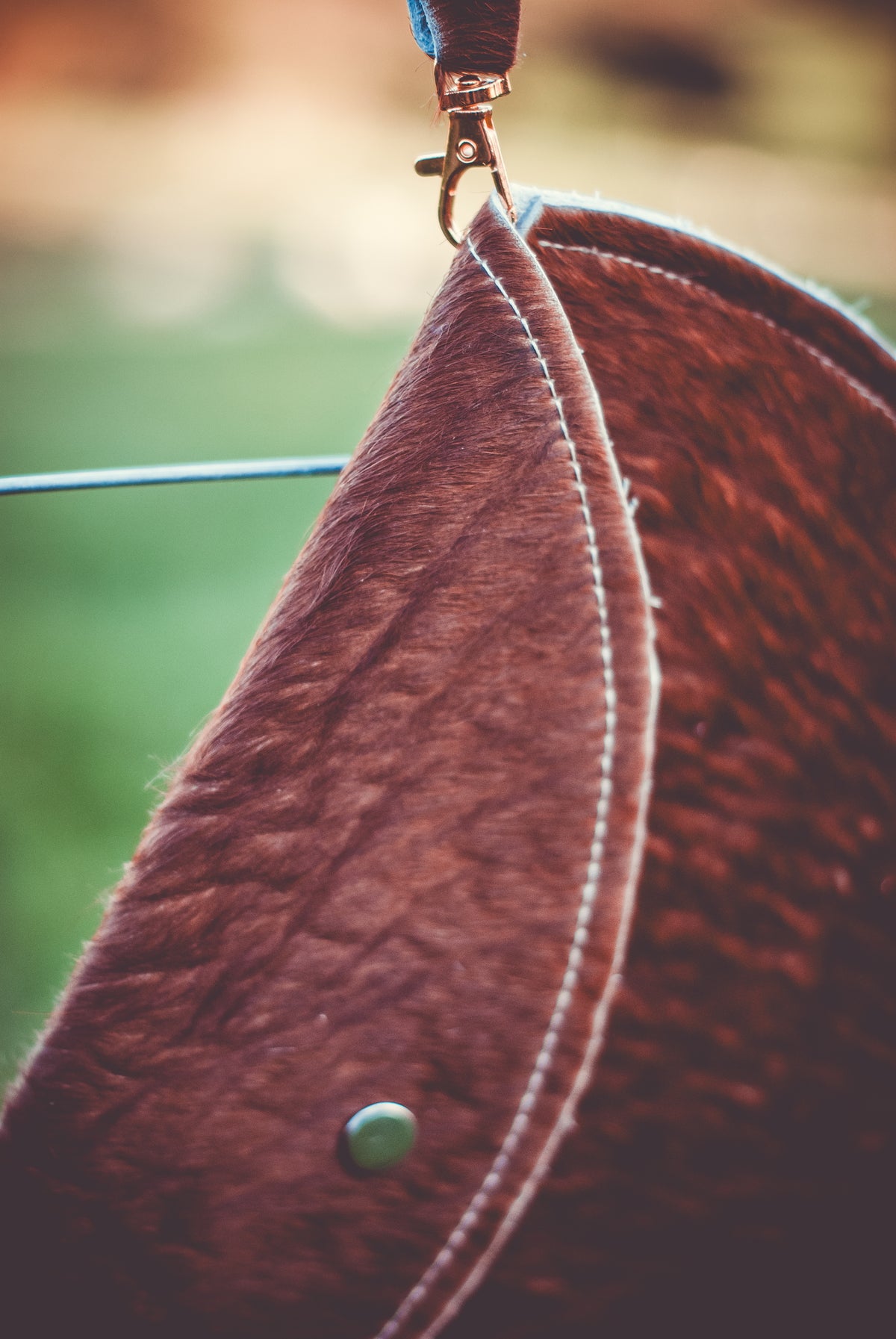 Brown cowhide moon clutch bag with leather strap and round snap button detail