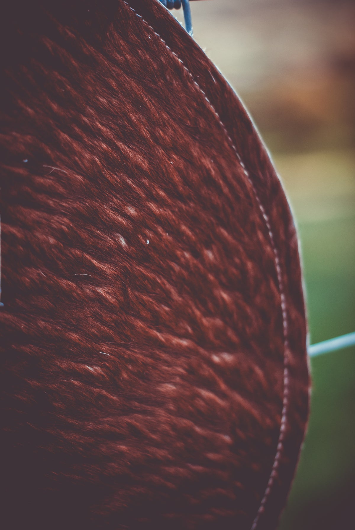 Brown cowhide moon clutch bag side view with visible curved stitching