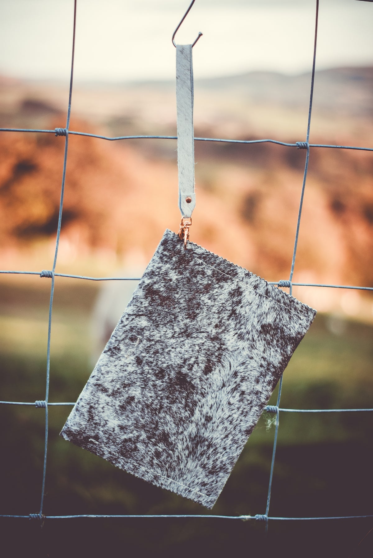 Cowhide clutch bag hanging: mottled gray flap with button closure and leather trim.