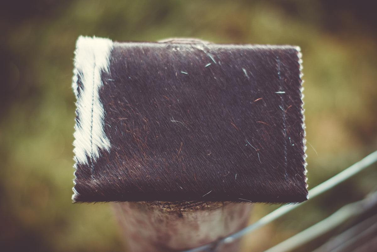 Small dark cowhide purse, rectangular body with white edge panel and stitched flap